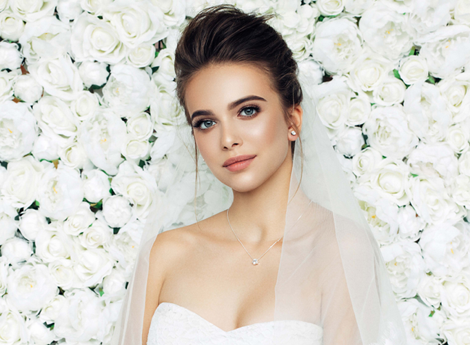 Bridal makeup look in front of a flower wall