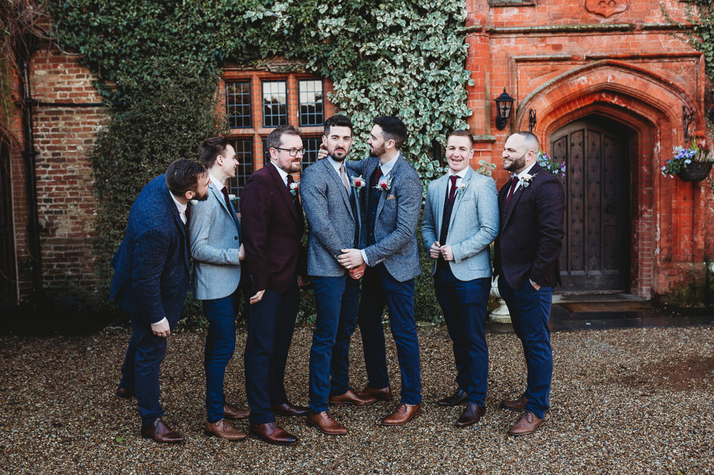 a group of groomsmen stood outside Woodhall Manor wearing blue or black suits