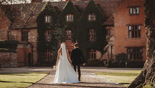 Wedding couple walking down the drive of Woodhall manor